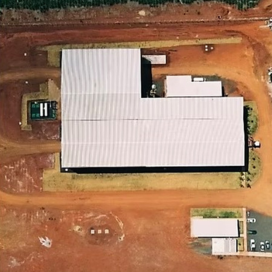 Vista aérea de uma edificação e da sua área técnica em solo de terra vermelha