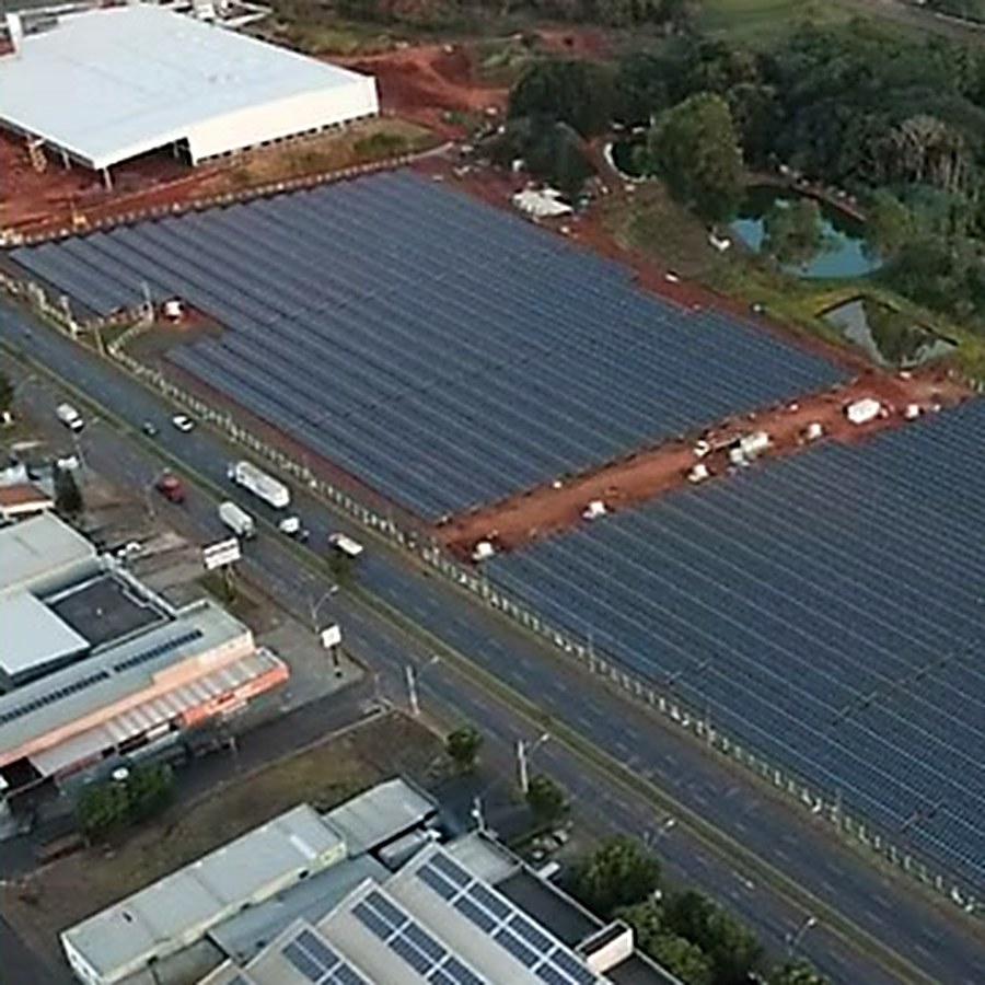 Vista aérea de uma usina fotovoltaica ao lado de uma rodovia